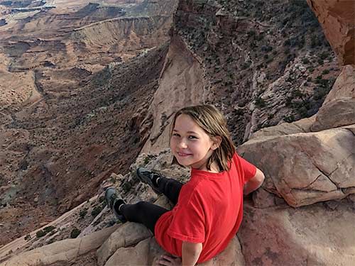 Erysse Elliott hangs feet overedge in Canyonlands National Park