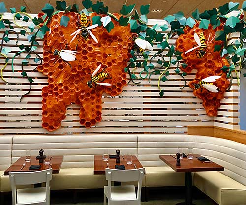 BuzzKill by artist Johnston Foster drapes walls throughout The Hive restaurant in Bentonville, Arkansas. The honeycombs, kudzu vines and bees reference the natural world of Northern Arkansas and serve as a fitting backdrop for menus that draw on local produce.
