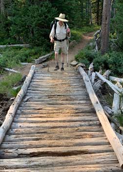 Man crossing a trail bridge in the Diamond Lake Wisderness
