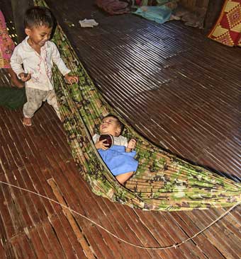 Cambodia Koh Trong Island boy rocks his sister in a hammock