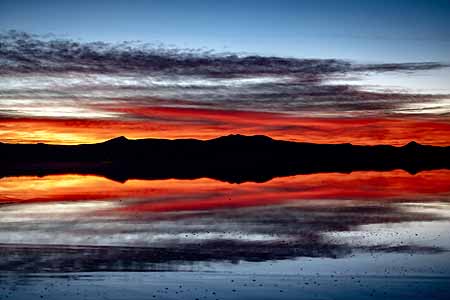 Bolivia, Red sunrise with water mirage on salt flats